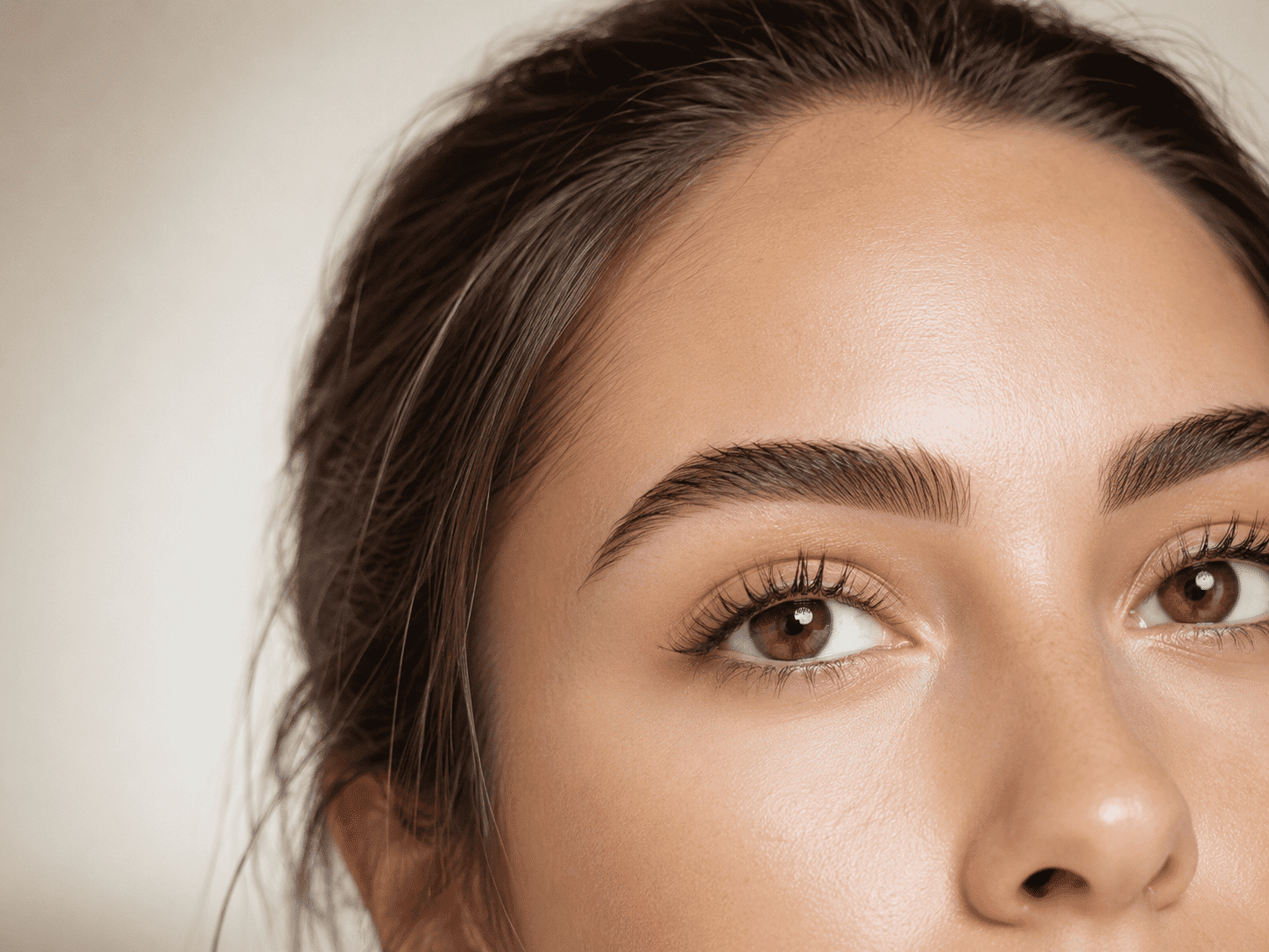 Close-up of a woman's face highlighting well-groomed eyebrows and smooth skin texture.